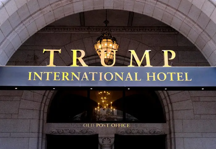 Workers began tearing down the gold letters of the Trump International Hotel's sign just hours after the sale of the DC hotel went through